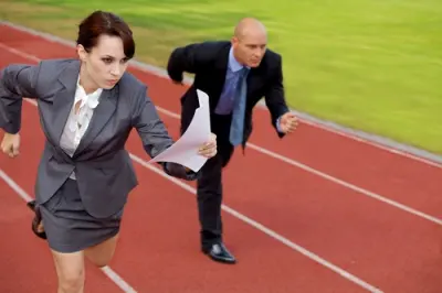 Two professionals in business dress running on a track lane carrying documents